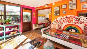 A vibrant living room with a colorful sofa, a wooden coffee table, and a bookshelf.
