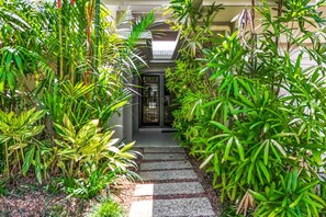 A pathway leading to a building entrance surrounded by lush greenery.