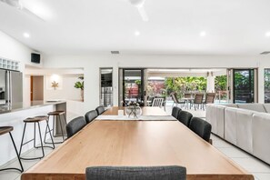A modern dining area with a long wooden table, black chairs, and a sofa.