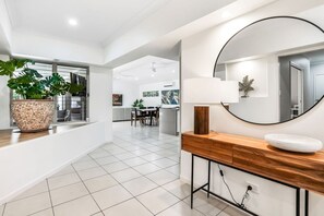 A modern kitchen with white cabinets, a wooden countertop, and a large window.