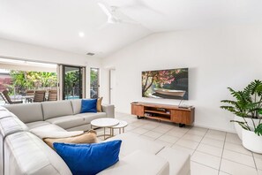 Una sala de estar moderna con un sofá grande, una mesa de centro y un televisor montado en la pared.