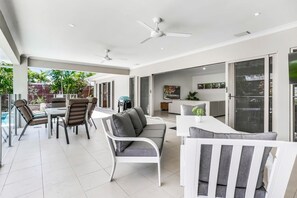 Un patio amplio con zona de comedor, un sofá y una televisión.
