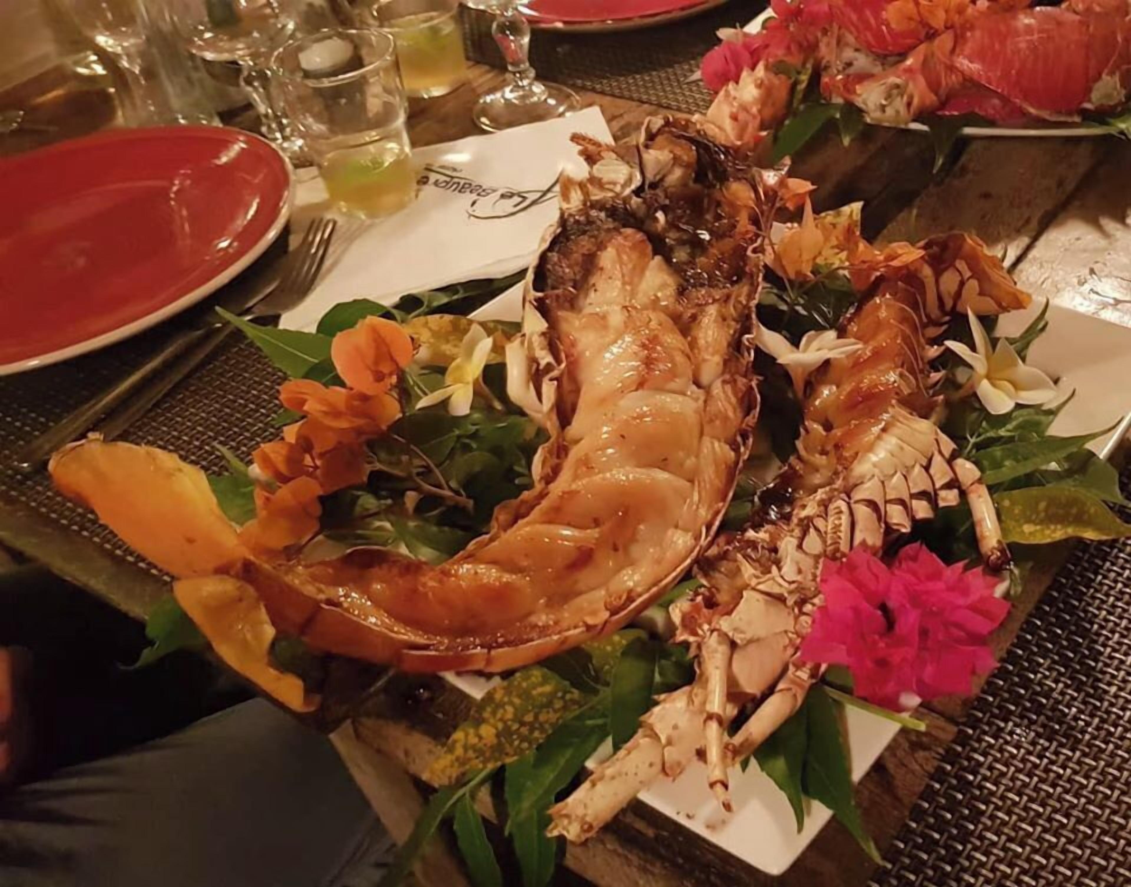 Una bandeja de mariscos con langosta, camarones y cangrejo, decorada con flores y hojas verdes.