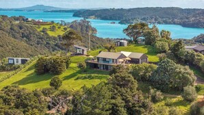 A residential area with houses surrounded by lush greenery and a large body of water in the background. - Woodside Bay Estate (Waiheke Island)