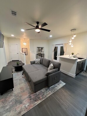 A modern living room with a gray sectional sofa, a small coffee table, and a ceiling fan. - Private studio in Cedar Park, TX (Cedar Park)
