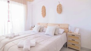 A bedroom with a large bed, two pillows, a nightstand with a lamp, and a window with curtains. - Calpe Playa | Arenal Bol Calpe (Calpe)