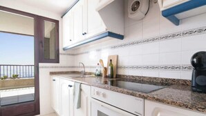 A kitchen with white cabinets, a granite countertop, and a view to the outside. - Calpe Playa | Arenal Bol Calpe (Calpe)