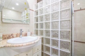 A bathroom with a marble sink, a glass shower enclosure, and a mirror above the sink. - Gran Sol | Playa Fossa Calpe (Calpe)