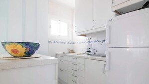 A kitchen with white cabinets, a colorful bowl on the counter, and a window above the sink.