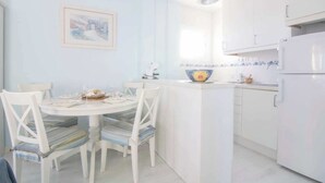 A kitchen with white cabinets, a dining table with chairs, and a painting on the wall.