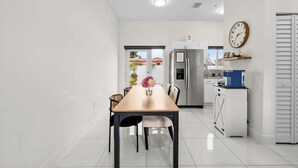 A modern kitchen with a dining table, chairs, and a refrigerator. - Family & Friends Fun-Huge Yard -Games -BBQ-FirePit (Miami)