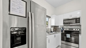 A modern kitchen with stainless steel appliances, white cabinetry, and a built-in oven. - Family & Friends Fun-Huge Yard -Games -BBQ-FirePit (Miami)