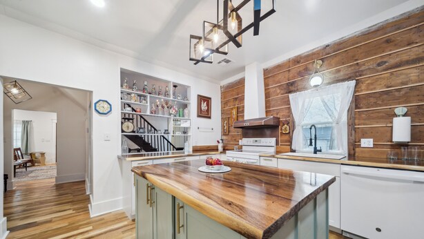 A modern kitchen with a wooden countertop, built-in shelves, and a staircase leading to another level. - 1800s Farmhouse—King Bed~Big Kitchen~Games & DVDs (Broken Arrow)
