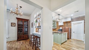 A kitchen with wooden flooring, a bar area with stools, and a cabinet with glass doors. - 1800s Farmhouse—King Bed~Big Kitchen~Games & DVDs (Broken Arrow)