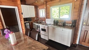 Ein Holzhütten-Interieur mit Küchenzeile, Esstisch und Stühlen.