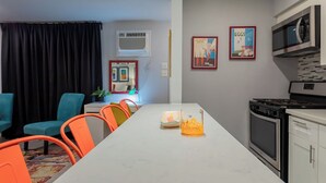 A modern kitchen with a white countertop, black stove, and white cabinets. There are two framed pictures on the wall and a microwave above the stove. - Montrose Amble Studio! Medical Center 02 ★★★★★ (Houston)
