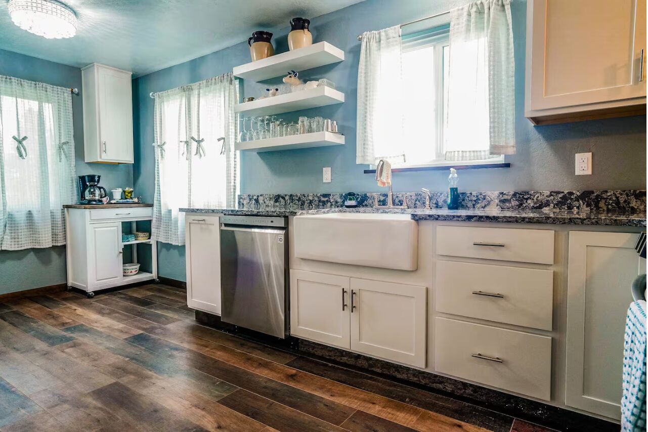 A kitchen with white cabinets, a dishwasher, and a countertop with a coffee maker.