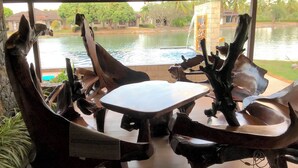 A dining area with a view of a body of water and trees.