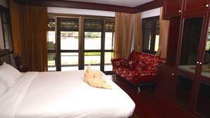 A hotel room with a large bed, a red sofa, and a view through a glass door.