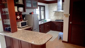 A kitchen with granite countertops, a refrigerator, a microwave, a stove, and wooden cabinets.