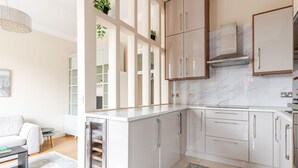 Een moderne keuken met witte kasten, een marmeren achterwand en een ingebouwde kookplaat.
