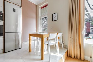 Enjoy meals in the well-equipped kitchen with a refrigerator, dining table, and comfortable seating.