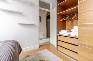 Cozy retreat with a neatly made bed and ample storage in a minimalist space.