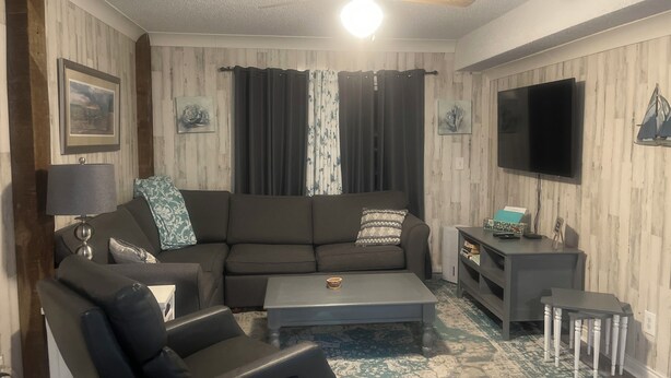 A living room with a sofa, coffee table, and TV stand. - Lucky Enough! Adorable apartment sleeps 5, no cleaning fee/ free beach parking! (Emerald Isle)