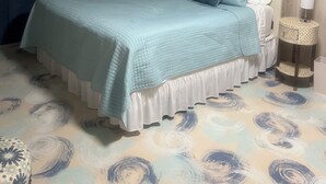 A bedroom with a bed, a nightstand, a wall-mounted painting, and a wardrobe. - Lucky Enough! Adorable apartment sleeps 5, no cleaning fee/ free beach parking! (Emerald Isle)