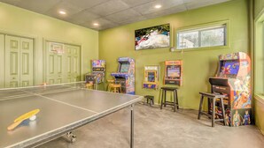 A room with a ping pong table, arcade games, and a window with blinds. - Best Views, Golf/Theater/GameRoom/HotTub7min to Town (Ellijay)