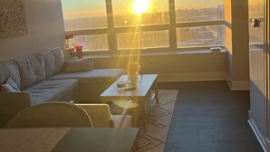 Een moderne woonkamer met een groot raam, een bank, een salontafel en een eettafel.