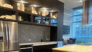 Een moderne keuken met een ingebouwde koelkast, oven en magnetron. Er is een groot kookeiland met een spoelbak en een raam erboven.