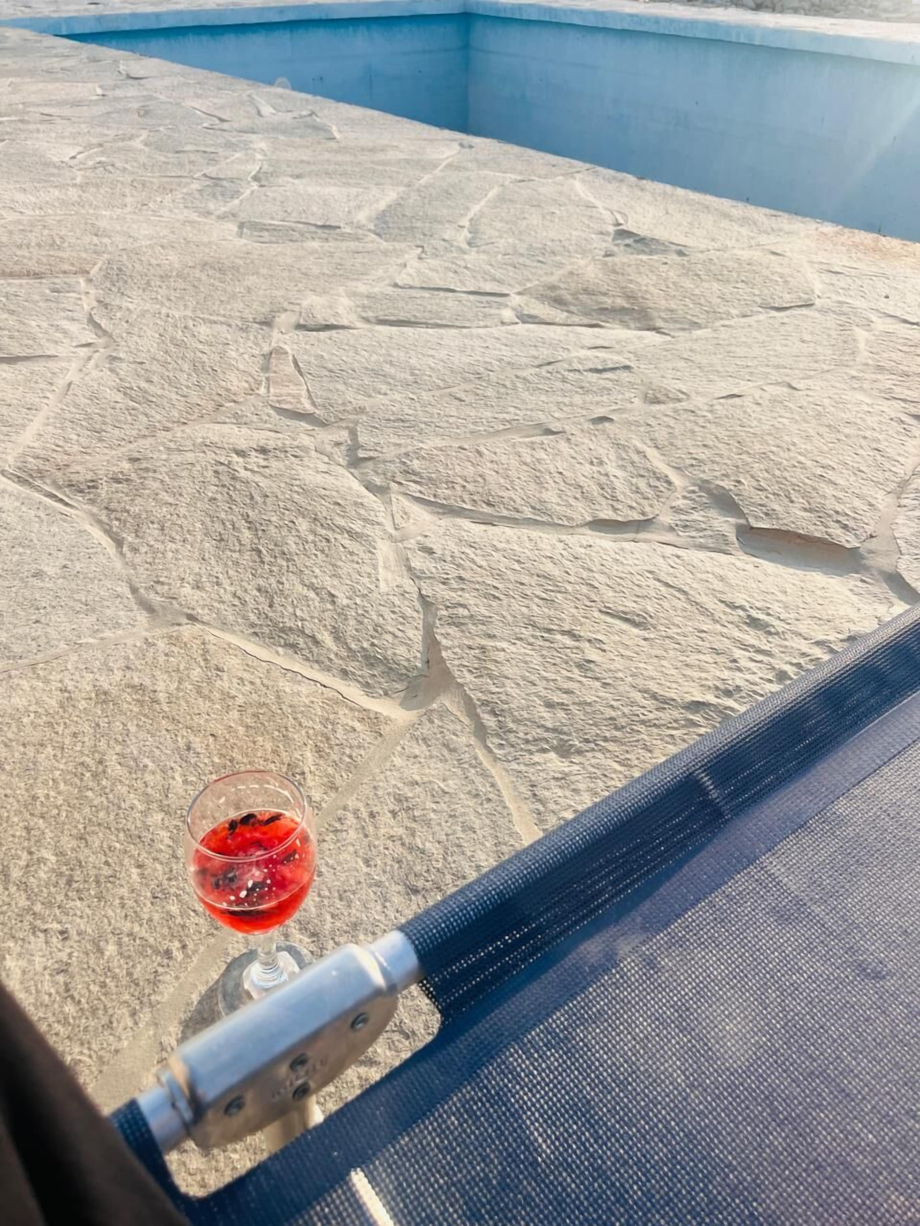 A stone-tiled floor with a glass table holding a red drink.