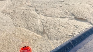 A stone-tiled floor with a glass table holding a red drink.