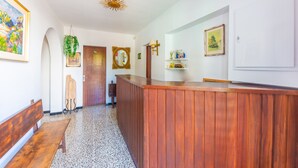 Ein Empfangsbereich mit Holztresen, einer Bank, einem Spiegel und gerahmten Kunstwerken an den Wänden.