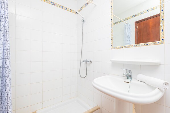 A bathroom with a shower, a sink, and a mirror.