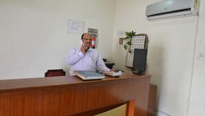 A reception desk with a man on the phone, a fire extinguisher, and an air conditioning unit on the wall. - Shama Tourist Resort (Gurugram)