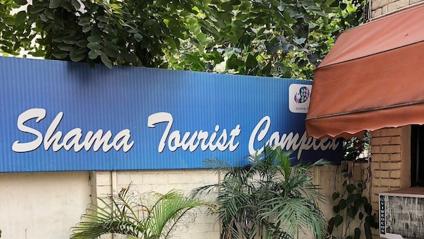 A sign for Shama Tourist Company with potted plants in front. - Shama Tourist Resort (Gurugram)