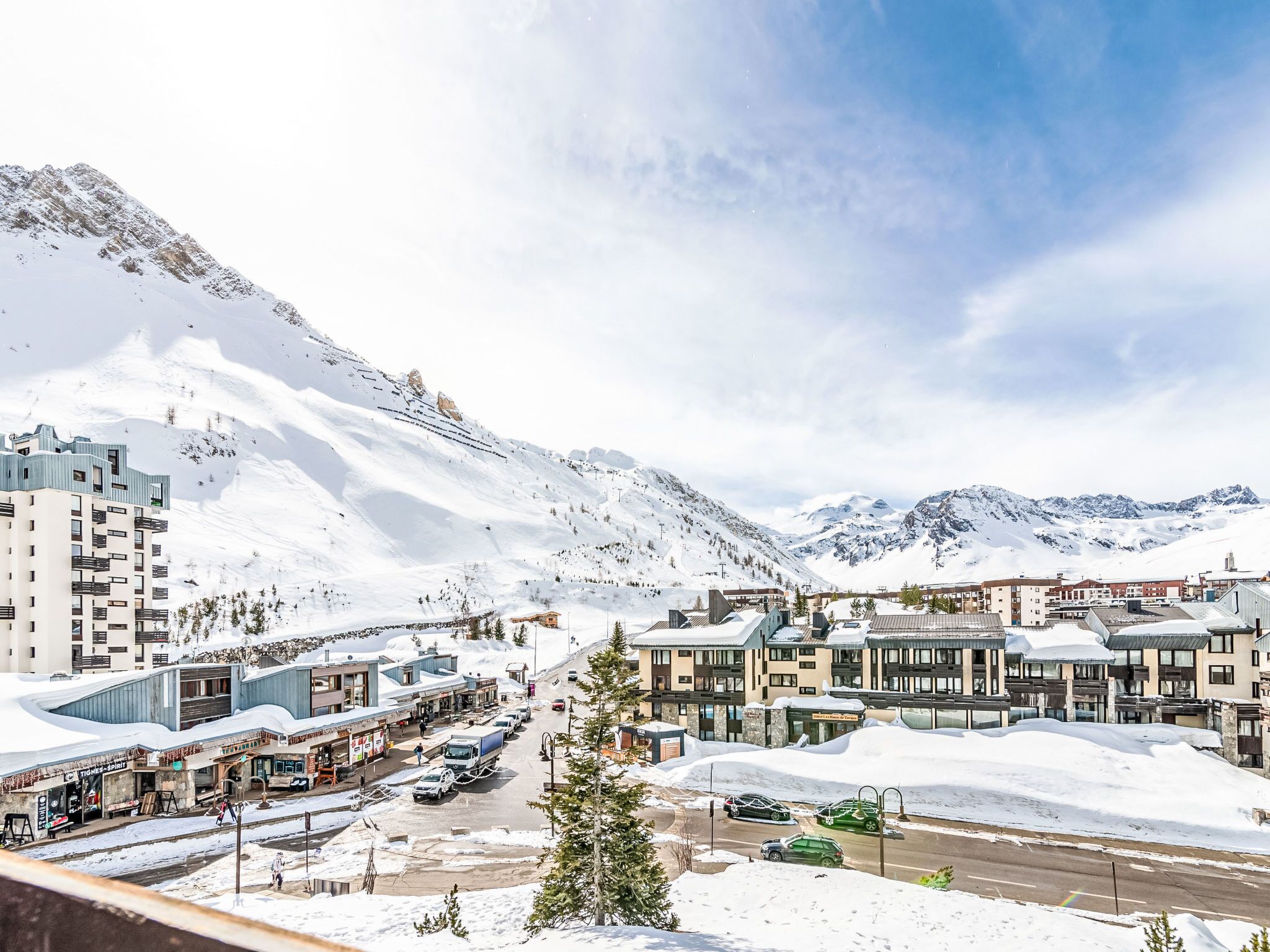 A snow-covered town with buildings, a road, and mountains in the background.
