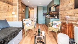 Ein gemütliches Zimmer mit einem Bett, einem Esstisch mit Stühlen, einer kleinen Küchenzeile und einem Wohnbereich mit einer Couch und einem Couchtisch.
