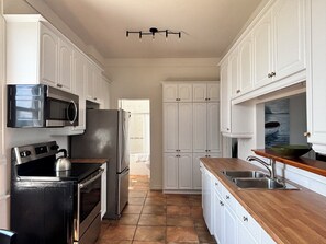 A kitchen with white cabinets, a stainless steel refrigerator, a microwave, and a kettle. - Mercantile House Guest Suite near Roblin Lake (hidden gem in PEC) ST-2023-0061 (Prince Edward)