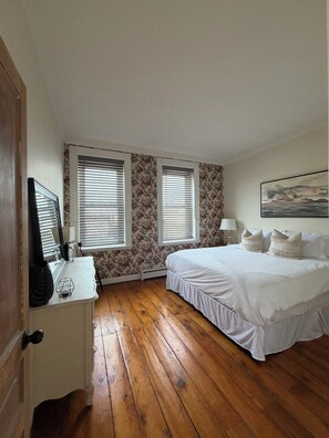 A bedroom with a bed, a desk, two windows with blinds, and a painting on the wall. - Mercantile House Guest Suite near Roblin Lake (hidden gem in PEC) ST-2023-0061 (Prince Edward)