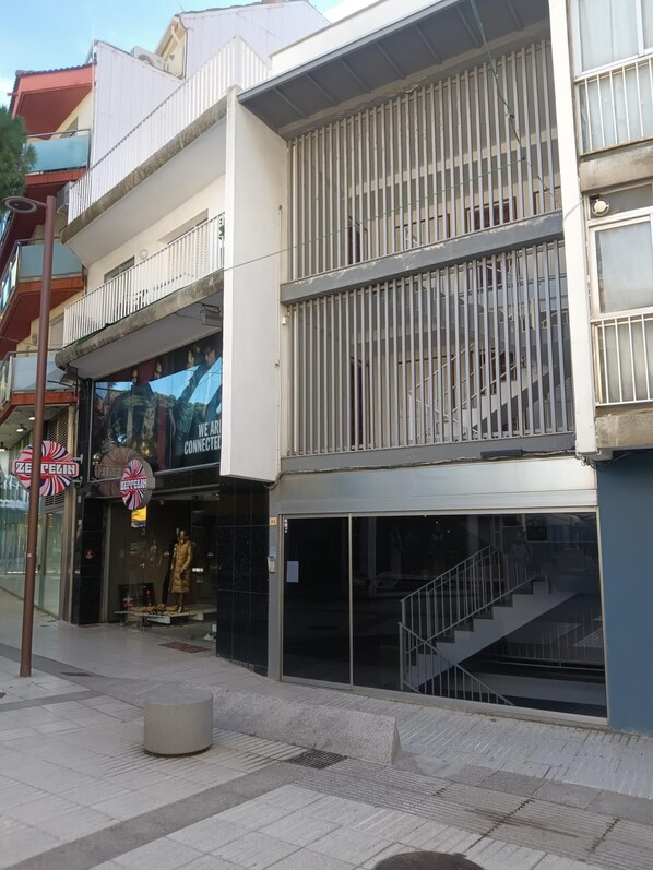 Un edificio de varios pisos con un espacio comercial en la planta baja y una escalera que sube a un nivel superior.