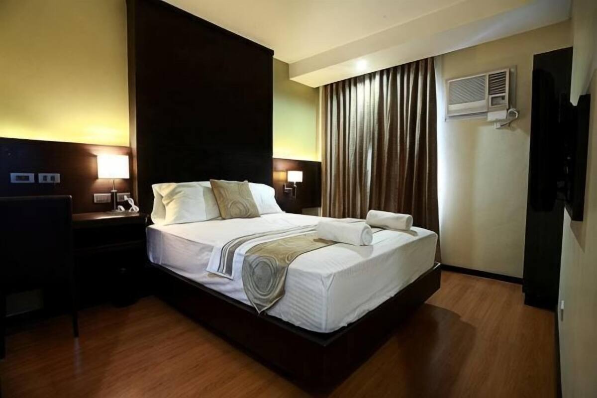 Ein Hotelzimmer mit einem großen Bett, Nachttischen, einem Schreibtisch und einem Fernseher.