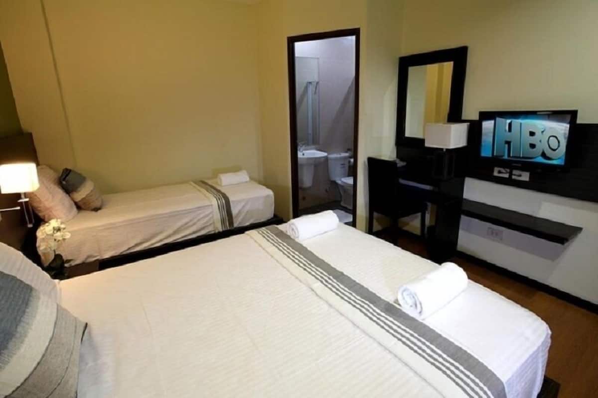 Ein Hotelzimmer mit zwei Betten, einem Fernseher, einem Schreibtisch und einem durch eine offene Tür einsehbaren Badezimmer.
