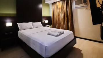 Una habitación de hotel moderna con una cama grande, dos mesitas de noche, un televisor de pared y una cortina.