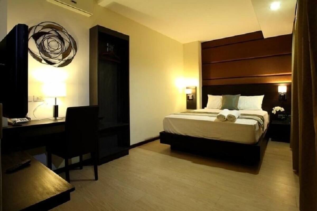 Ein Hotelzimmer mit einem Bett, Nachttischen, einem Schreibtisch mit Stuhl und einem Wandbild.