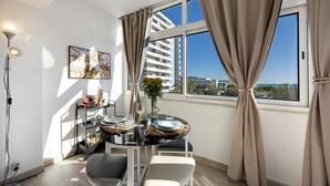 A modern dining area with a table set for two, a floor lamp, and a large window with curtains. - Apartment 'Torralta' with Sea View, Wi-Fi and Air Conditioning (Alvor)