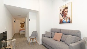 A modern living room with a grey sofa, a small grey chair, a flat-screen TV, and a painting on the wall. - GuestReady - Flat near the Marina of Valencia (Valencia)