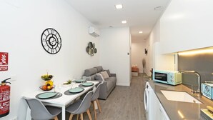 A compact living space with a dining area, kitchenette, and a sofa. - GuestReady Essential - Flat near Valencia Marina (Valencia)